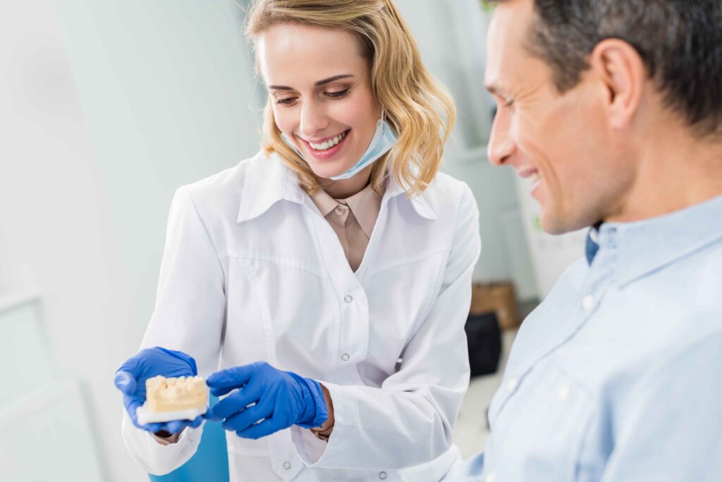 Dentist explaining a dental model to a patient during consultation.