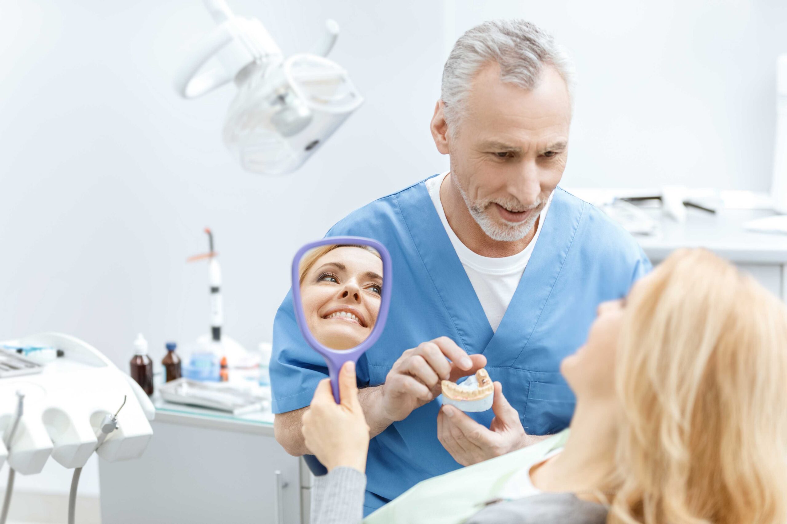 Dentist showing a dental model to a smiling patient during an oral health consultation